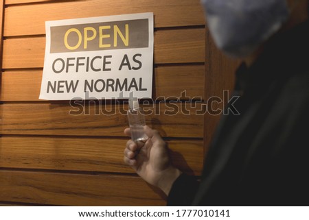 Business owner wears masks and hand is holding alcohol gel to label for open office. The concept is opening office after the COVID-19 situation, follows the new normal life. select tive focus