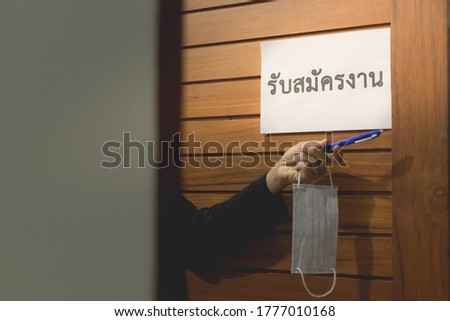 Translate word is : Recruitment. hand is extending the mask and a pen. The concept is opening for applying jobs after the COVID-19 situation, follows the new normal life. selective focus