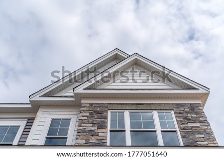 New house facade with double gable roof  stone veneer siding large symmetric sash window with grills Royalty-Free Stock Photo #1777051640