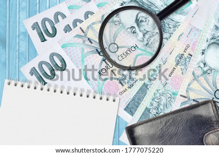 100 Czech korun bills and magnifying glass with black purse and notepad. Concept of counterfeit money. Search for differences in details on money bills to detect fake