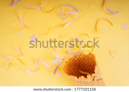 Celebrate party poppers. Fun crackers with serpentine sparkles for festive congratulations and evening parties. Ice cream waffle cone. Over bright yellow background.