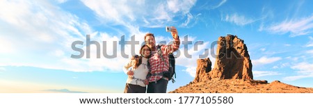 Selfie tourists taking photo with mobile phone at summit of mountain hike panoramic. Nature trek couple hikers hiking with backpacks in Europe panoramic banner.