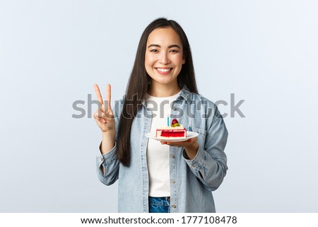 Social distancing lifestyle, covid-19 pandemic, celebrating holidays during coronavirus concept. Happy smiling asian birthday girl holding bday cake and show peace sign