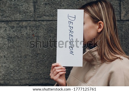 Woman holding white sheet paper labeled word Depression in hand