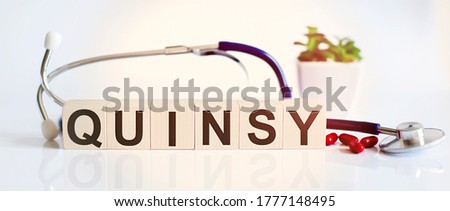 QUINSY the word is written on wooden cubes and sthetoscope and piils . Medical concept