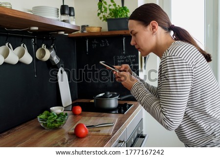 Woman taking pictures of her food on phone in kitchen