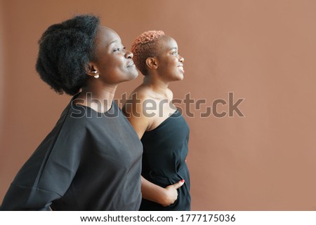 Two african friends are looking in the same direction on brown studio background, BLM