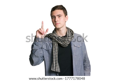 A young man in a Manatee shirt, black t-shirt and trousers, plaid scarf, isolated on white points the finger at copyspace