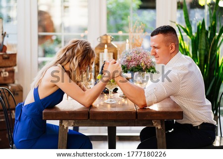 two cheerful lovers out who's in charge and fight on hand at a romantic dinner. arm wrestling