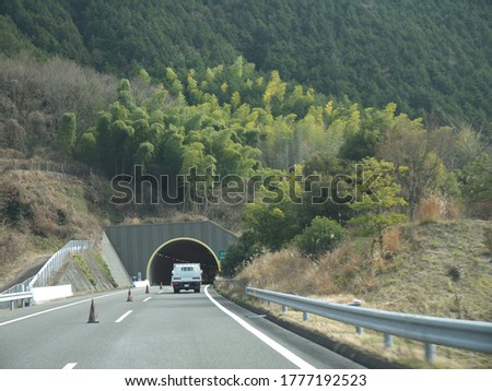 Driving on highway, distant mountains, tunnel entrance ahead, sunny day, travelling on Shikoku, Japan