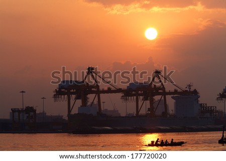 Silhouettes of port constructions crane  on dark sunset with reflection water 