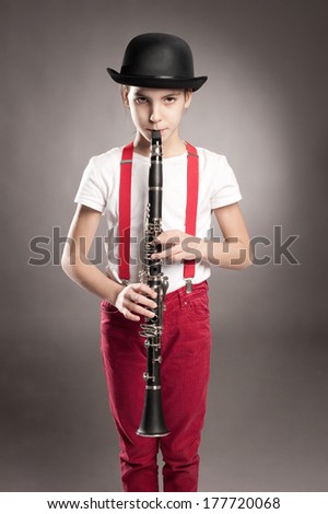little girl playing clarinet on a gray background