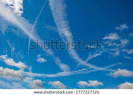 Panorama of white clouds in a blue cloudy sunlit bright sky with contrails in summer
