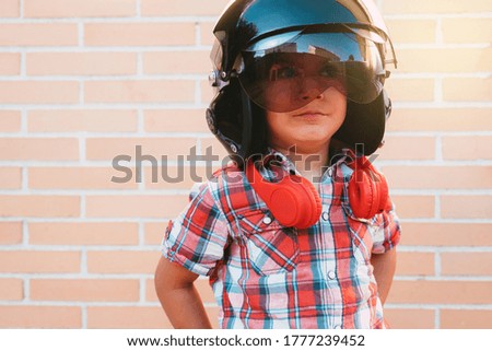 portrait of boy with Russian pilot's helmet on brick wall