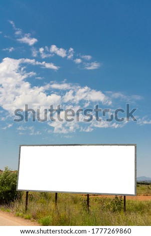 One billboard next to a road in the field and blue sky with clouds. Vertical image with horizontal white copy space.