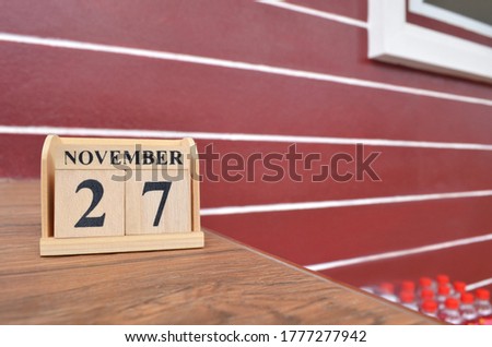 November 27, Number cube with wooden table beside the wall.