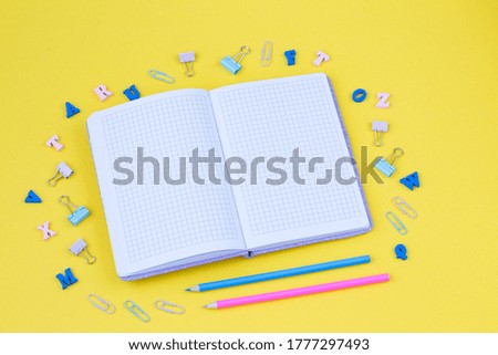 on a yellow background an open notebook, letters, pencils and paper clips 