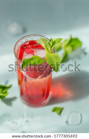 Glass of strawberry soda drink on light blue background. Summer healthy detox lemonade, cocktail or another drink background. Low alcohol, nonalcoholic drinks, vegetarian or healthy diet concept.