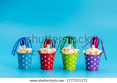 a front view fresh popcorn inside multicolored baskets on the blue background cinema movie snack seeds