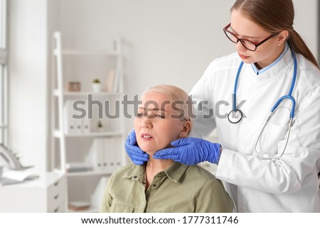 Doctor examining senior woman with thyroid gland problem in clinic Royalty-Free Stock Photo #1777311746