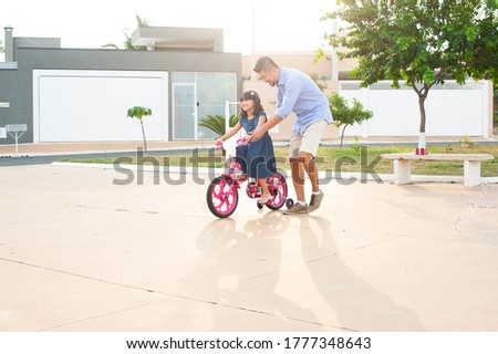 Father and daughter outdoors. Showing affection and love. Father teaching daughter to ride a bicycle. Father's Day.