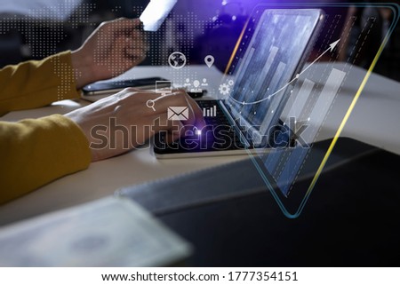 Businesswoman working on digital tablet 
computer with financial chart from the screen and network interface icons, Business analytics and financial technology concept, Background toned image blurred.