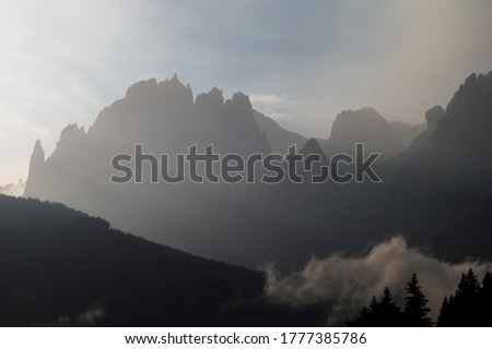 Catinaccio group seen by Pozza di Fassa inside the Dolomite mountain range with a cloudy sky in the background, Italy