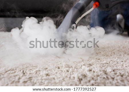 Selective focus of vacuum cleaner with hot steam on carpet at home Royalty-Free Stock Photo #1777392527