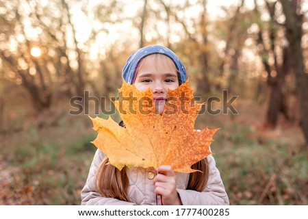 Autumn vibes, hello autumn concept. Stylish 7 years old girl walking in the empty park among golden trees, social distance, sunny weekend, beautiful nature outside Royalty-Free Stock Photo #1777400285