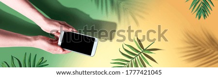 Smartphone with tropical palm leaves and shadow - flat lay