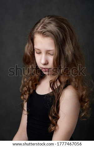 Young girl in black top looking downwards