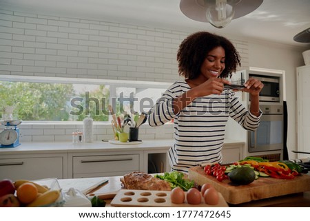 Side video of young successful female food blogger taking picture of freshly slices and chopped vegetables in modern kitchen