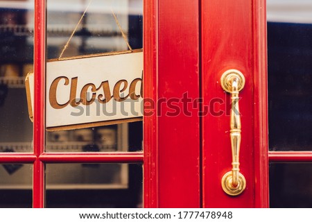 Label 'Closed' notice sign wood board hanging on door front coffee shop. Beautiful wooden door of red color in the city. Elegant vintage burgundy colour front door in an old town.