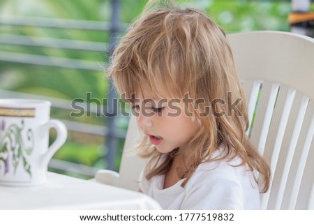 portrait of a little girl while having breakfast on the terrace, note shallow depth of field