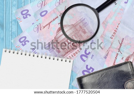 50 Ukrainian hryvnias bills and magnifying glass with black purse and notepad. Concept of counterfeit money. Search for differences in details on money bills to detect fake