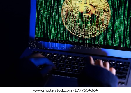 Hacker with computer hacking and stealing data information, Selective focus image on keyboard, Bitcoin logo and binary code as background. Bitcoin cryptocurrency security and privacy issues.