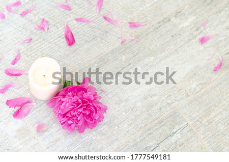 Beautiful pink peony flowers and white candle on white grey stone background with copy space for your text top view. Greeting card, SPA and romantic concept.