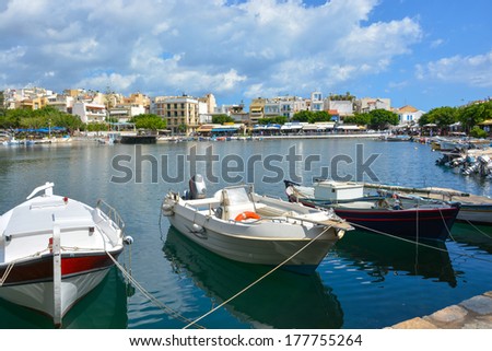 Boats at Vulismeni lake in Agios Nikolaos, Greece, Crete. Multi-colored houses, restaurants, coffee shops in the city of Agios Nikolaos, the view of the lake and the city.