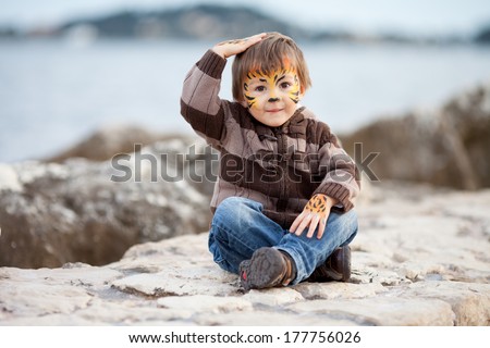 Little boy with painted face on the beach