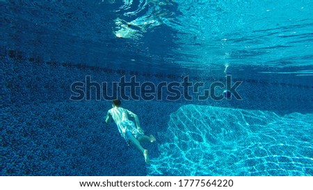Young male swimming underwater in pool
