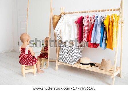 Dressing closet with clothes arranged on hangers. Colorful wardrobe of newborn, kids, toddlers, babies full of all clothes. montessori wardrobe Royalty-Free Stock Photo #1777636163