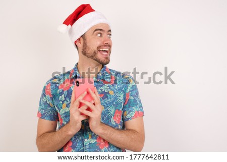 Copyspace photo of Young caucasian man wearing hawaiian shirt and Christmas hat over isolated white background pretty attractive gorgeous sweet lovely beautiful girlfriend stupor with something 