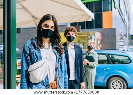 Three different people wearing face masks waiting in line orders in public place, during virus pandemia, keep safe distance outdoors during quarantine. Two female in medical masks in summer time. Royalty-Free Stock Photo #1777659038