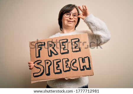 Young down syndrome woman holding protest banner of free speech for communication rights doing ok sign with fingers, excellent symbol