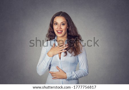 Stunned young woman looking at camera isolated on studio gray background. Model girl with long wavy curly hair in blue formal shirt. Closeup portrait. Positive human emotion, face expression, 