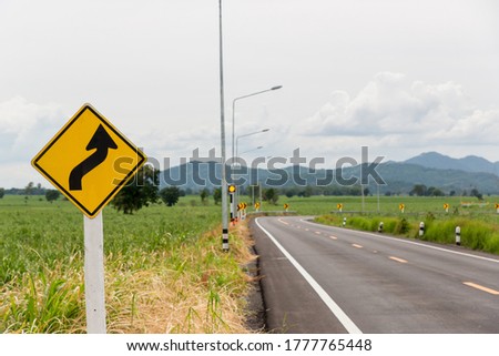 Sign curved road on the way at the natural  Field Or Meadow. Warning attention Right curve sign at Rural highway. Road sign showing curves ahead