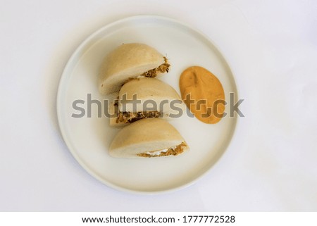 Top view of a steamed buns with pork cheeks and orange souce. Gourmet dish on a table.