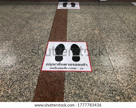 Floor Sticker for help reduce the risk of catching Covid-19, advice hospital customers to stand in space. Translation of letters: “Standing here to reduce the risk of catching Covid-19”