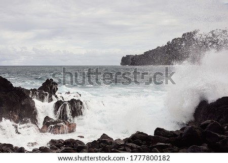 Wave splashing against lava rocks on a lava beach on the Big Island in Hawaii.