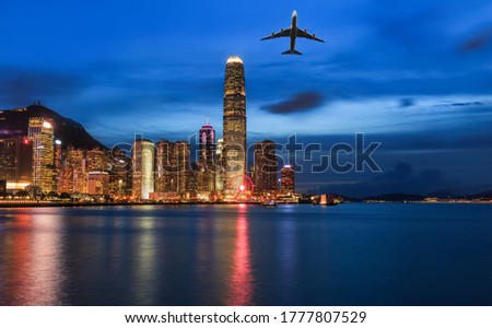 Airplane flying over skyscrapers Cityscape in Hong Kong with illuminated buildings at twilight. Victoria harbour view at night in Hong Kong.